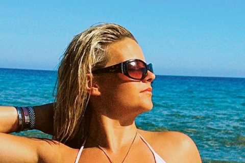 Busty ring girl Apollonia Llewellyn almost slips out of tiny bikini as she tops up her tan on the beach